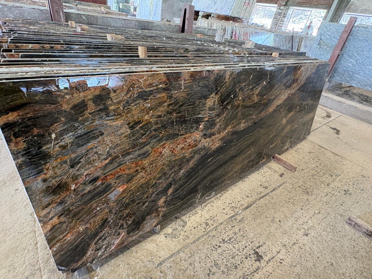 Polierte Platte aus Alaska Granite mit dunkler Grundfarbe und markanter goldener Aderung